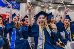 Shenandoah University grads raise their diplomas.