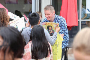 Shenandoah University Children's Literature Conference speaker John Schu signs books for schoolchildren at a Rally for Reading to kick off the virtual/in-person conference in April.