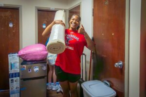 A Shenandoah University student carries a rug into a residence hall.